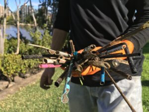 Handful of muddy straws, orange glove, mangrove background