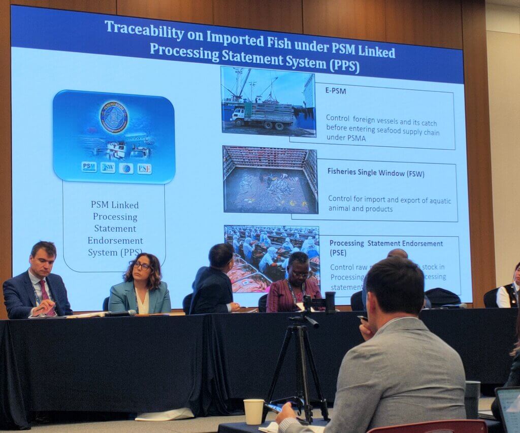 Six people sit at a desk in front of a screen with the title Traceability on Imported Fish under PSM Linked Processing Statement System (PPS).